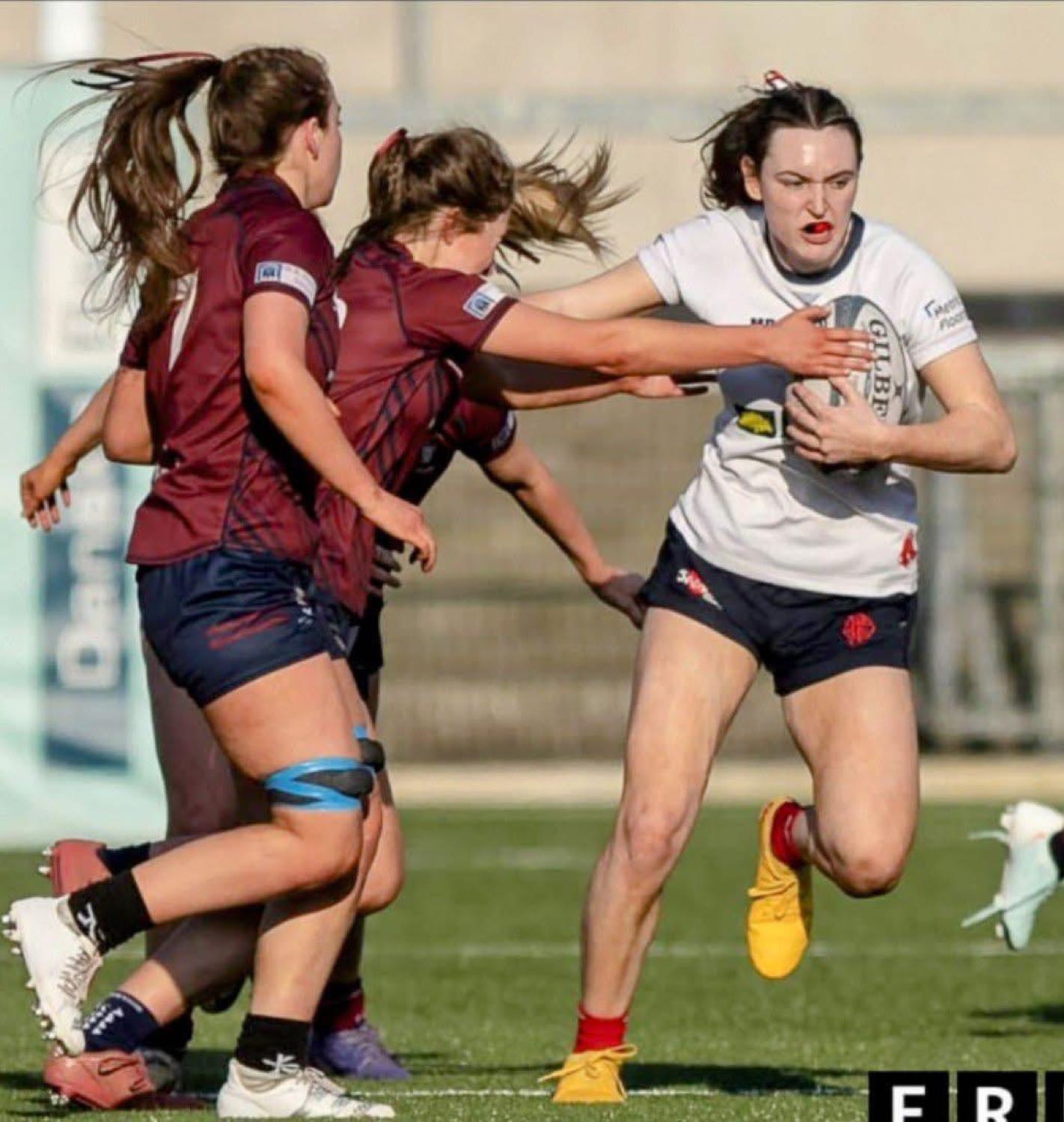Malone senior women in action, breaking through a tackle